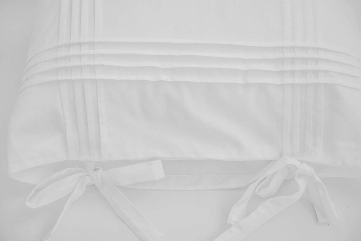 Travesseiros de algodão branco adornados com pregas e arcos