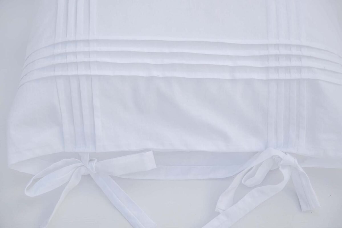 Travesseiros de algodão branco adornados com pregas e arcos