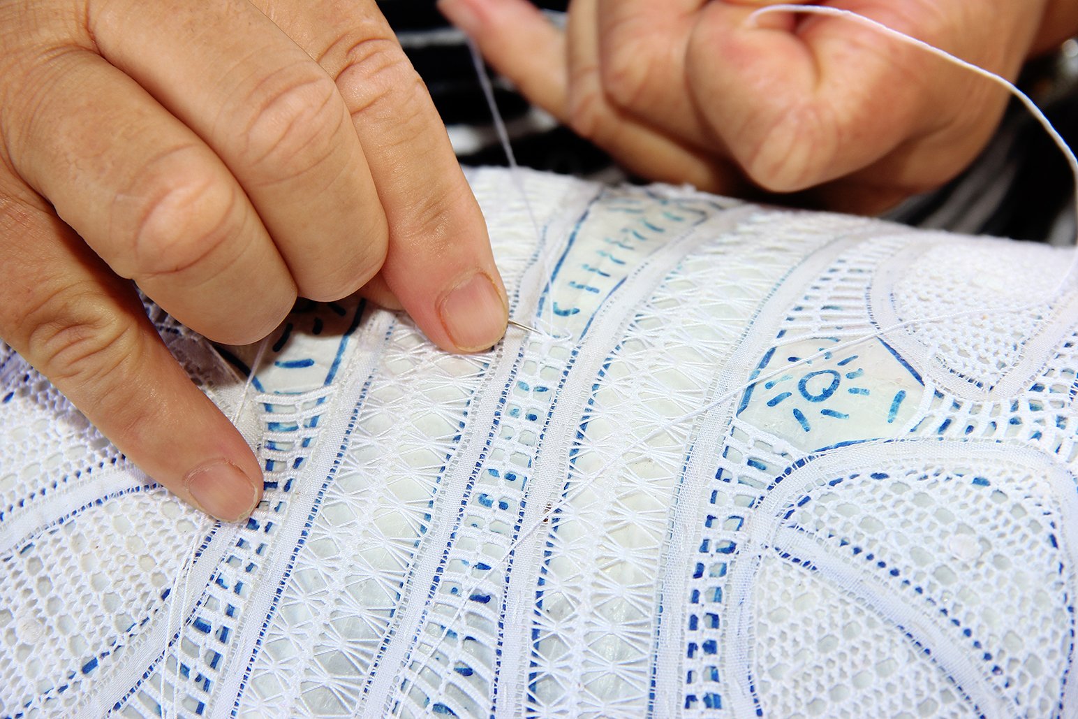 About Us picture of a woman's hands making needle lace
