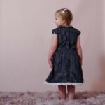 sweet girl wearing a navy blue polka dot dress with a lovely peter pan collar adorned with handmade lace trims