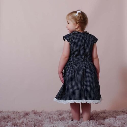 sweet girl wearing a navy blue polka dot dress with a lovely peter pan collar adorned with handmade lace trims