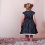 sweet girl wearing a navy blue polka dot dress with a lovely peter pan collar adorned with handmade lace trims