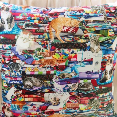 dreamy cats among loads of sewing stuff, including bright floral fabrics